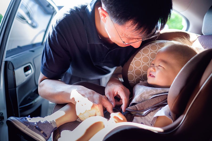 Insurance Quote - Closeup View of Happy Father Putting the Seatbelt on His Baby Son in the Car
