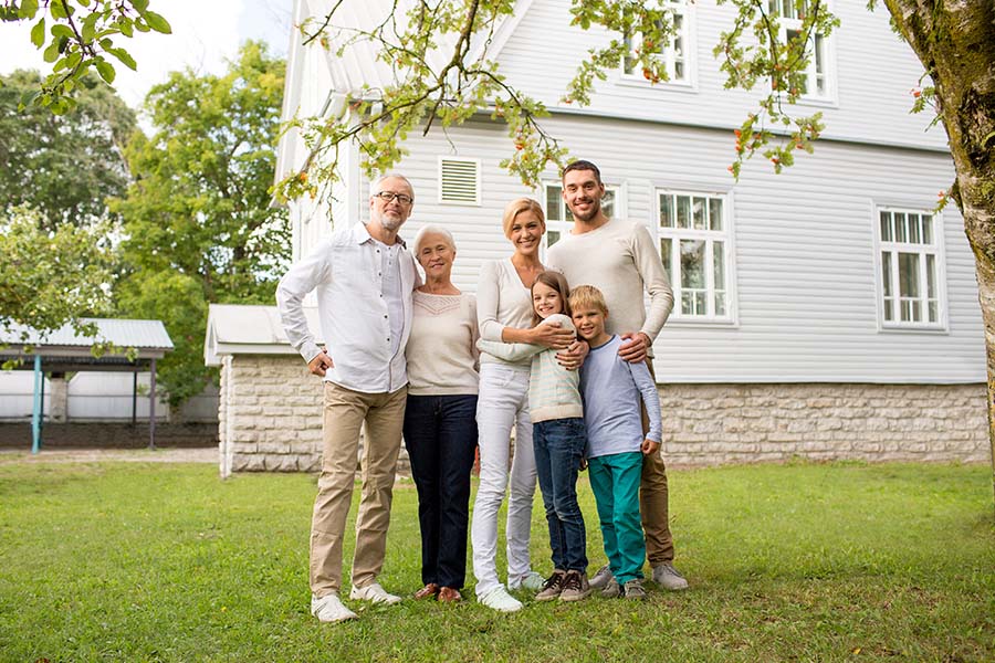 Personal Insurance - Cheerful Extended Family Standing Outside Their Home on the Green Grass